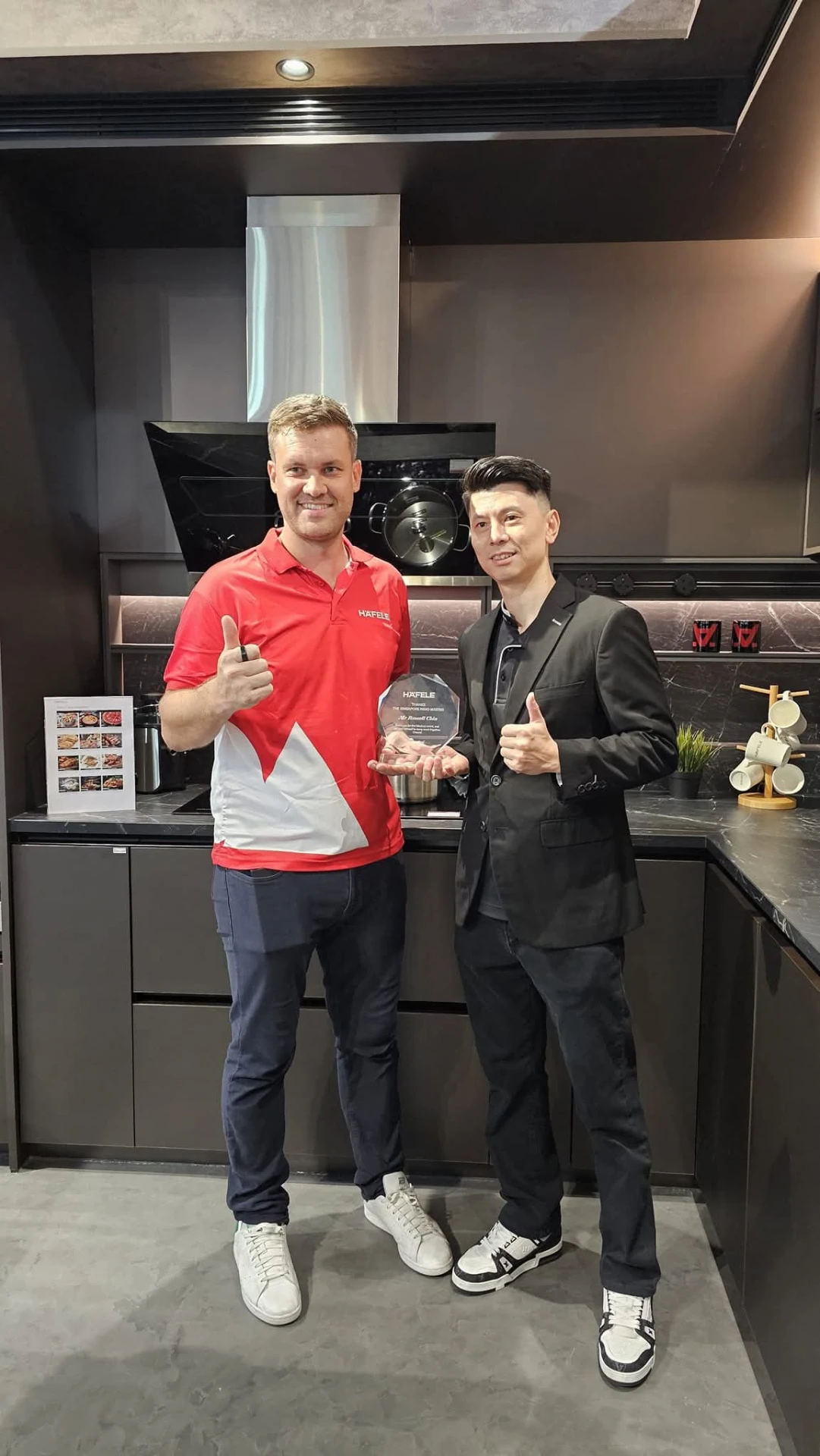 Russell Chin with Häfele Singapore receiving an award in a modern kitchen showroom