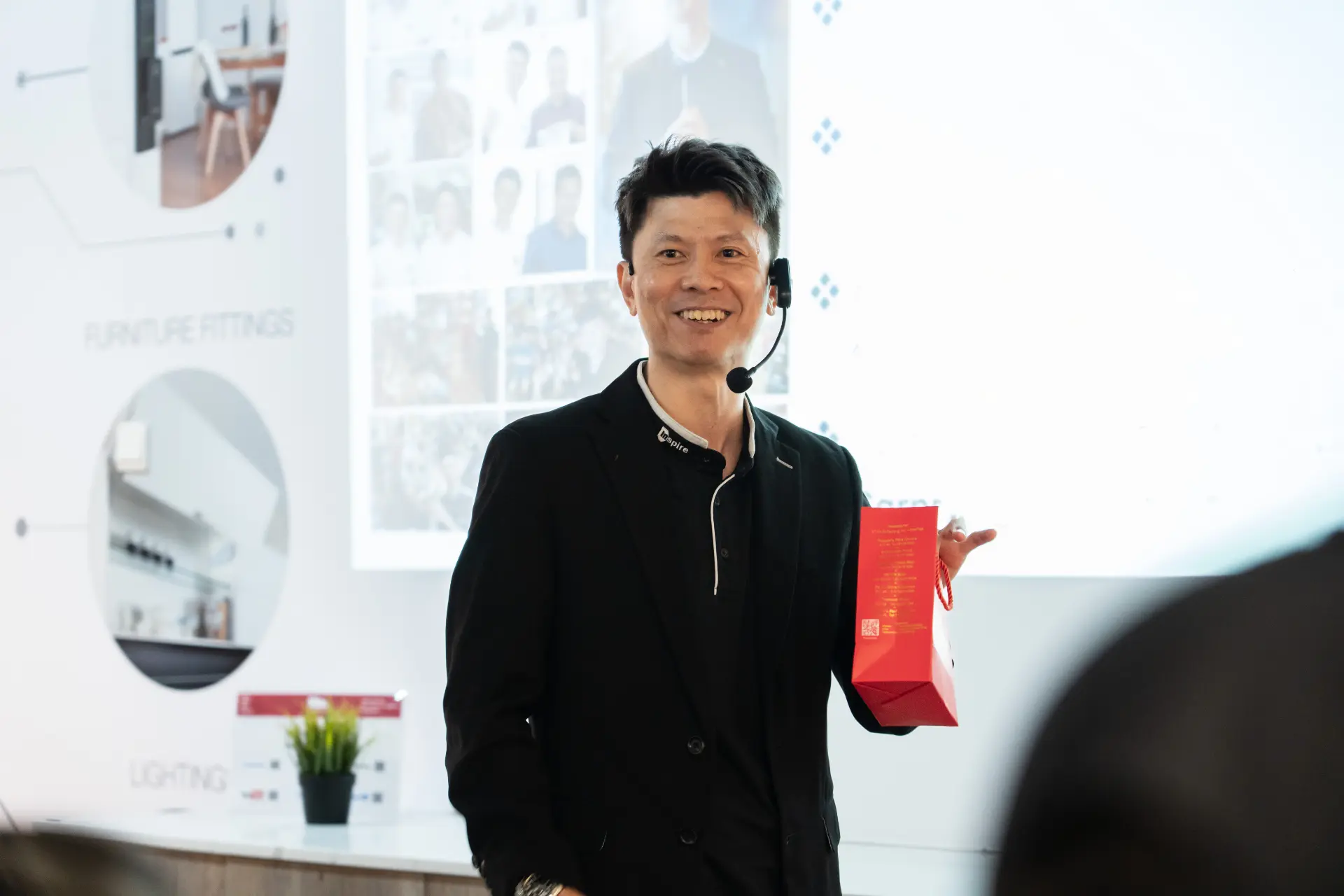 Russell Chin holding a gift bag for an attendee at a renovation talk